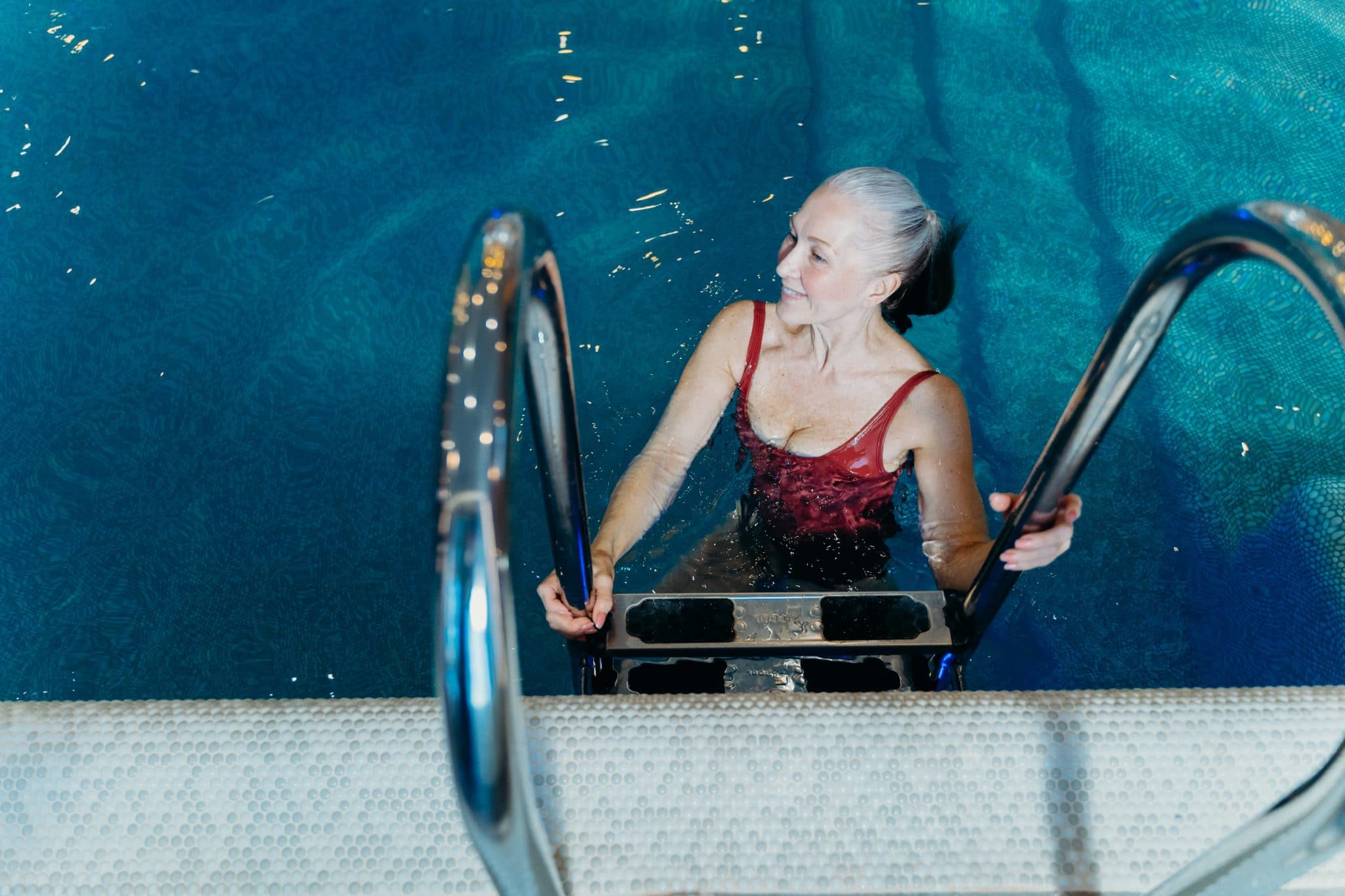Woman using a ladder to get into the pool.