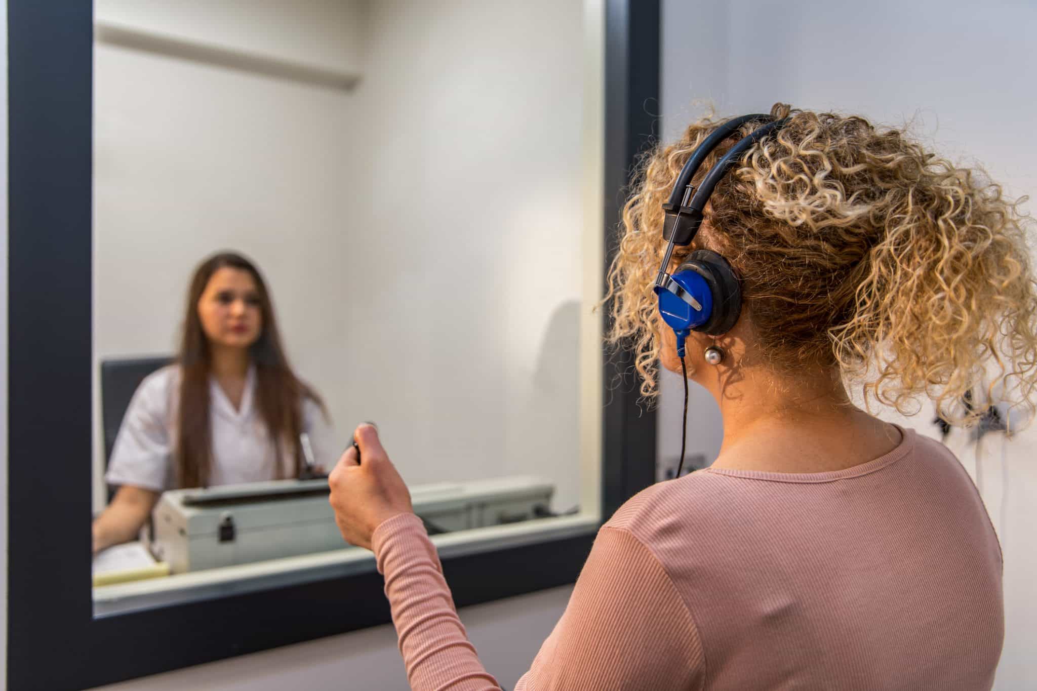 An audiologist performs a hearing test on a patient.