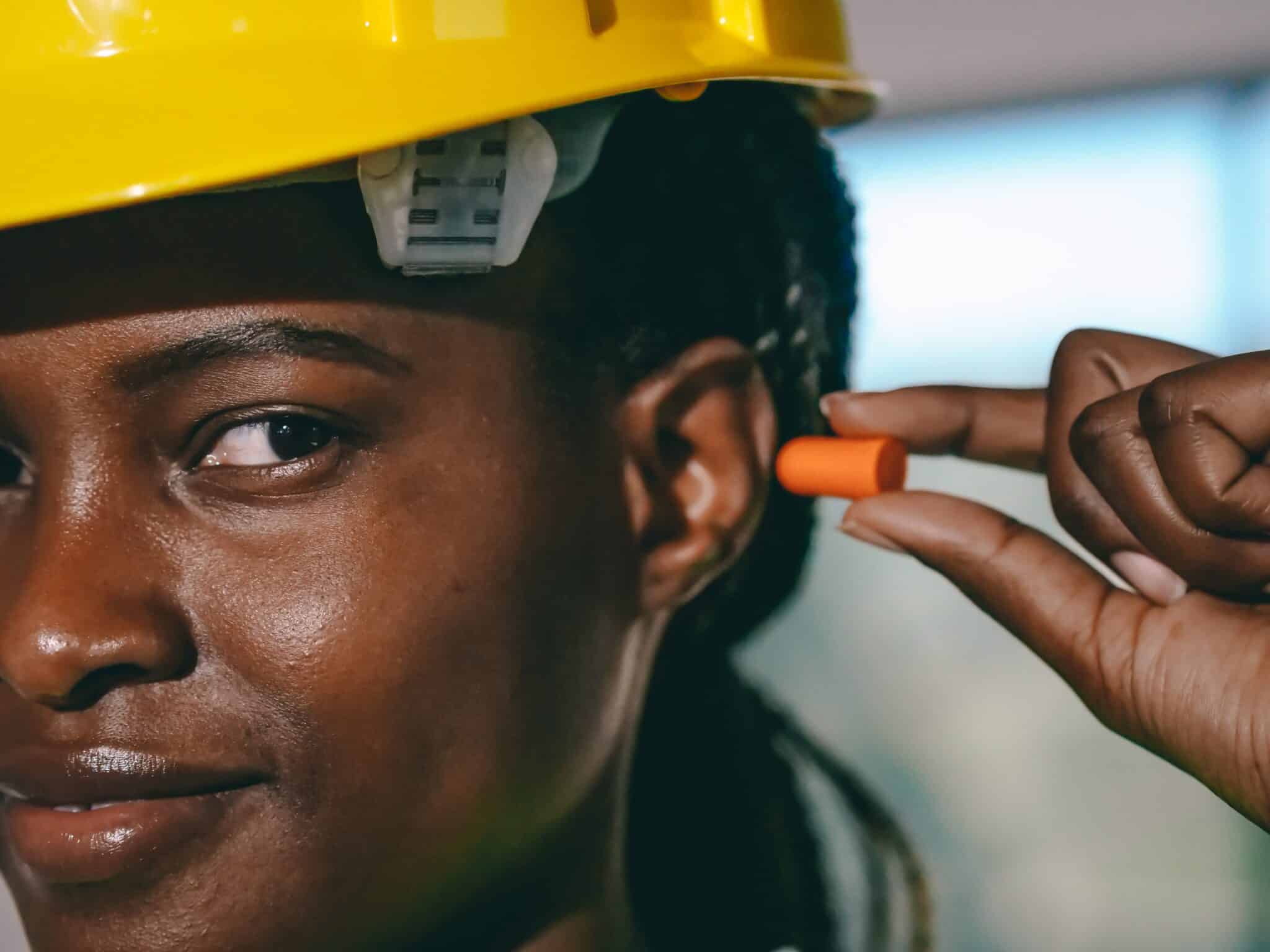hearing-protection-earplug Female construction worker putting an earplug into her ear.