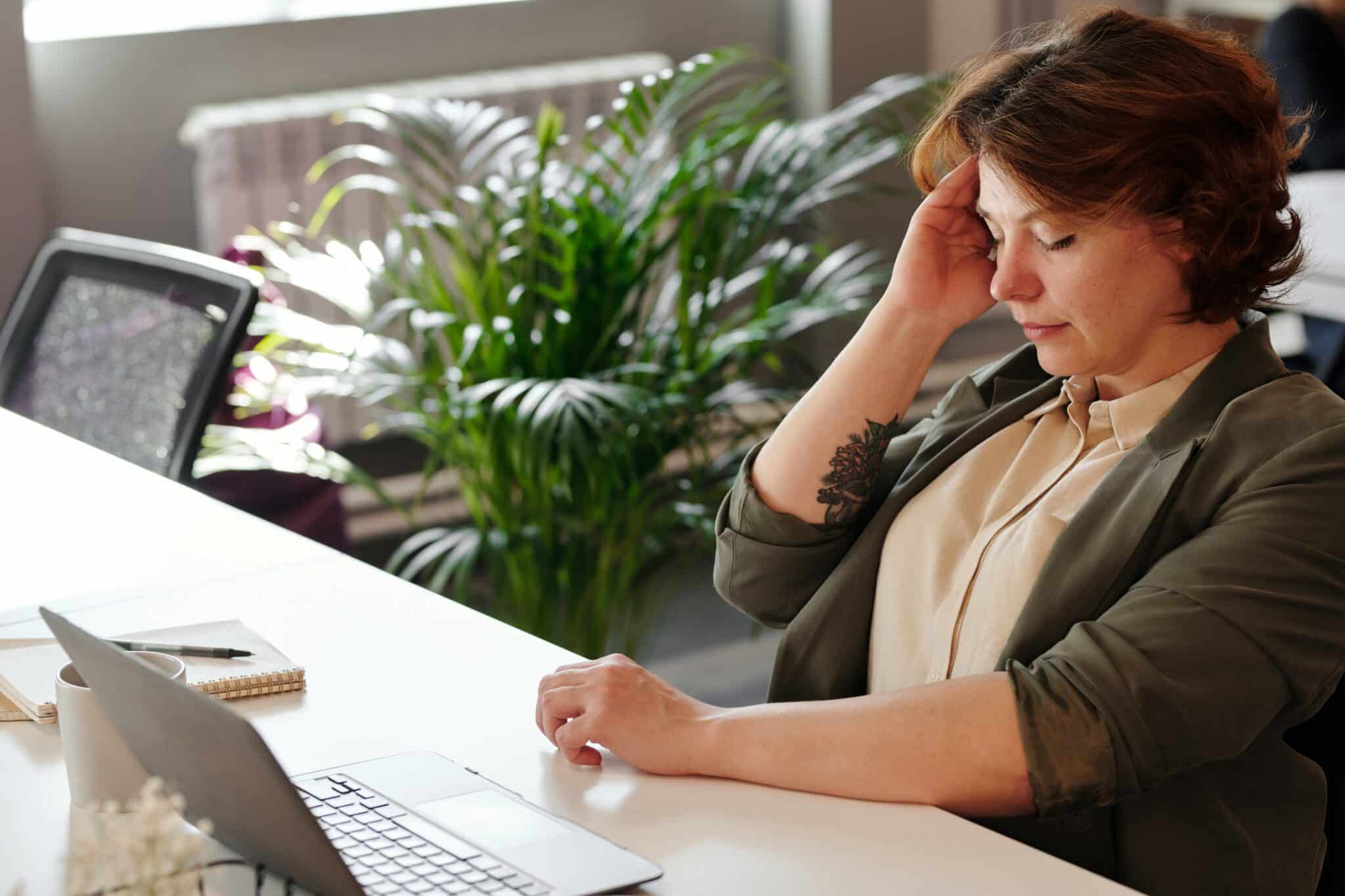 Woman experiencing a migraine at work.