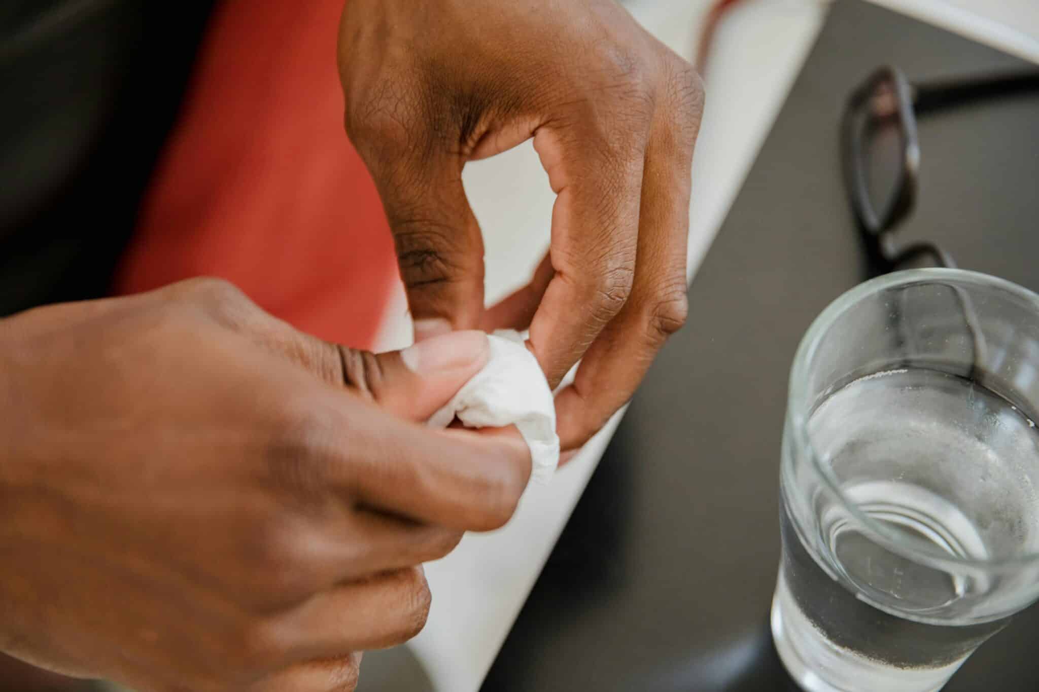 A pair of hands cleaning a hearing aid with a soft cloth.