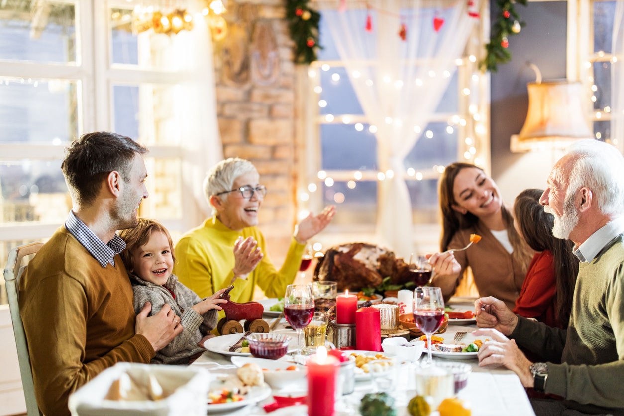 Happy family eating a holiday dinner in a well-decorated dining room.